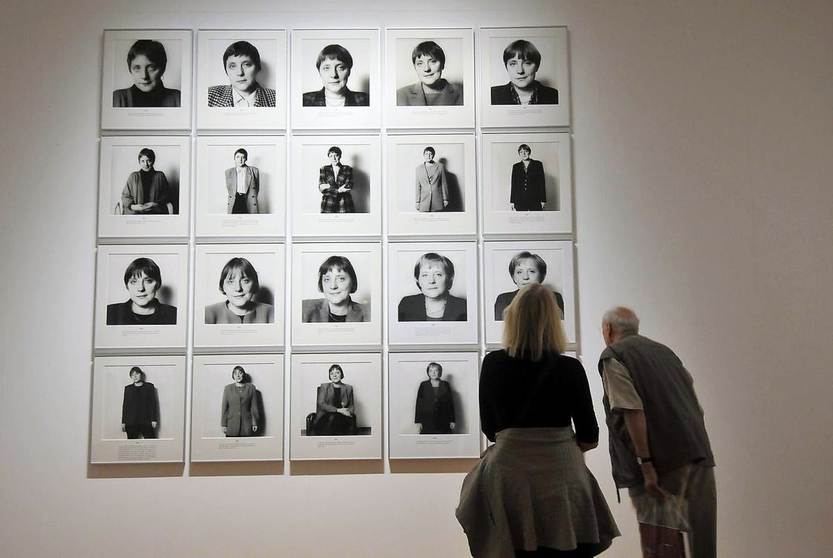 Двое посетителей рассматривают серию фотографий под названием «Spuren der Macht» («Следы власти») с изображением канцлера Германии Ангелы Меркель, сделанную немецким фотографом Херлинде Кёльбл в Берлине, 16 июля 2009 г. Посетители рассматривают серию фотографий под названием «Spuren der Macht» («Следы власти») с изображением канцлера Германии Ангелы Меркель
