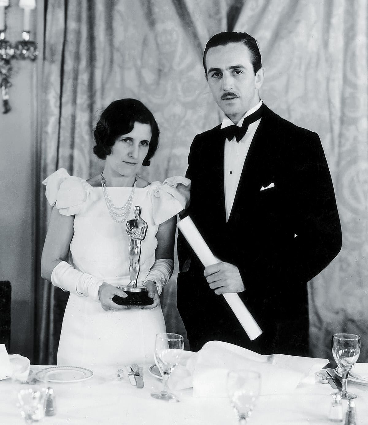 Уолт Дисней с женой, Лилиан Баундс, которая держит один из его Оскаров, 1935 г. Уолт Дисней с женой, Лилиан Баундс, которая держит один из его Оскаров